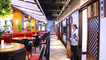 Un restaurante con cabinas y mesas, una persona de pie cerca de la entrada, y una pared con diseño.