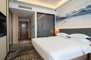 A hotel room with a large bed, a painting on the wall, and a door leading to another room. - Kaisheng Hotel (Xiangtan)
