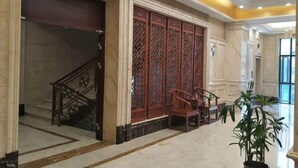 A lobby with a staircase, a decorative red screen, and a potted plant. - Yaocheng Guesthouse (Dongzhi)