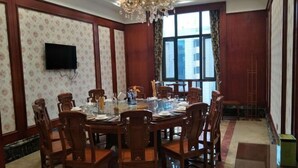 A conference room with a round table, wooden chairs, a chandelier, a TV mounted on the wall, and a large window with curtains. - Yaocheng Guesthouse (Dongzhi)