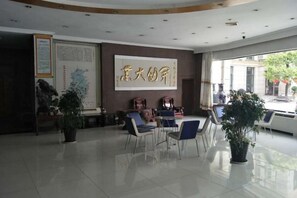 A hotel lobby with a reception desk, seating area, and a large framed artwork on the wall. - Yaocheng Guesthouse (Dongzhi)
