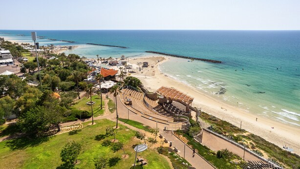 An aerial view of a coastal area with a beach, a theater, and surrounding greenery. - MIKLAT Elegant Apt with Balcony & Sea View by FeelHome (Netanya)