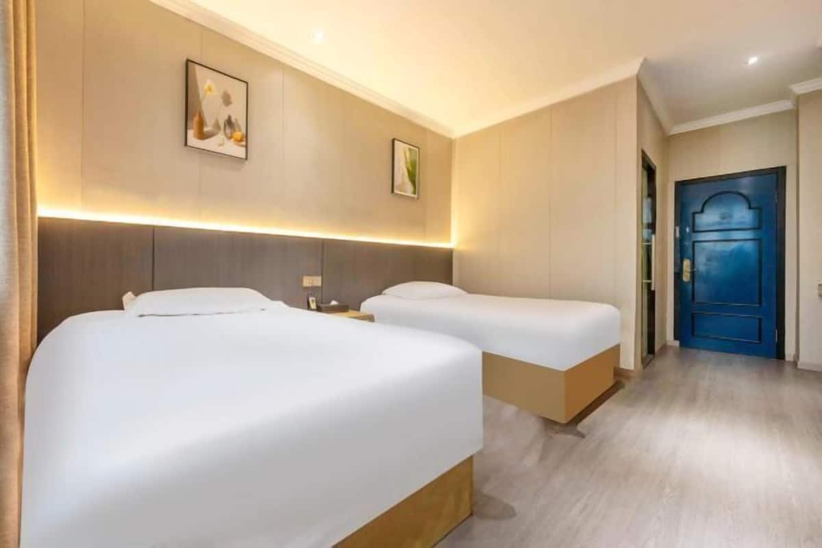 Ein Hotelzimmer mit zwei Betten, einer blauen Tür und einer Wandleuchte.