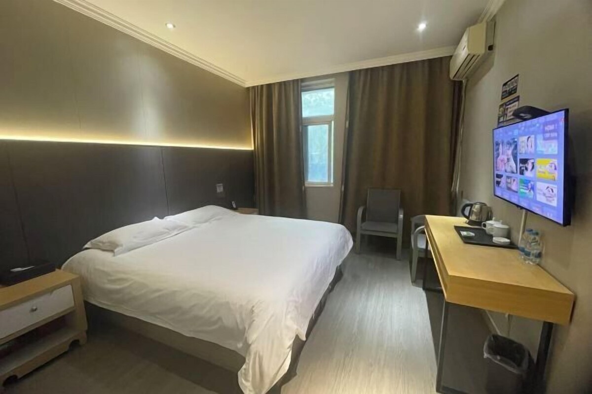 Ein Hotelzimmer mit Bett, Schreibtisch, Stuhl, Fernseher und Fenster.