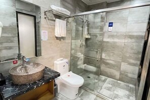 Ein Badezimmer mit Marmorwaschbecken, Toilette und einer Duschkabine.