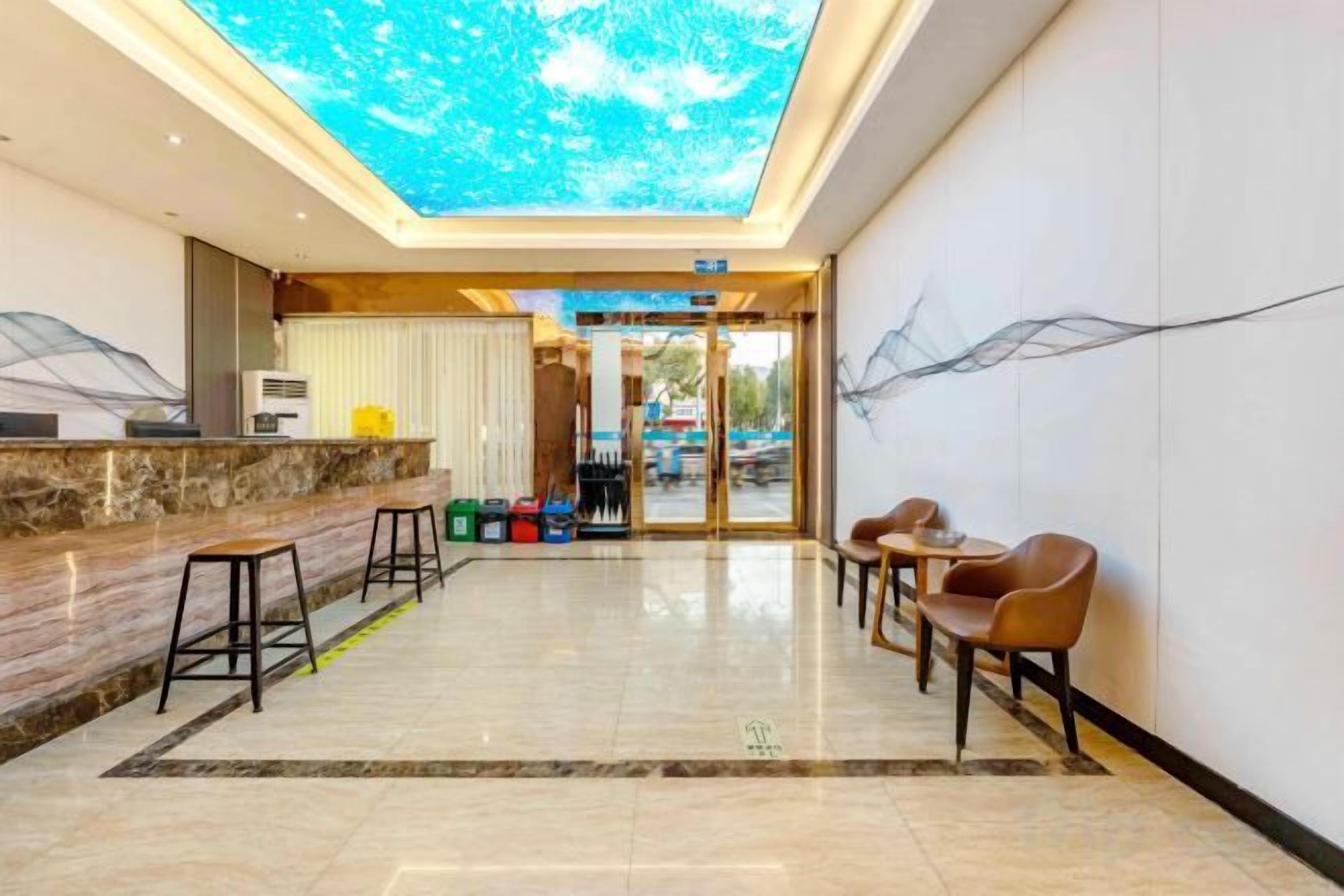A hotel lobby with a reception desk, seating area, and a ceiling with a natural light effect.