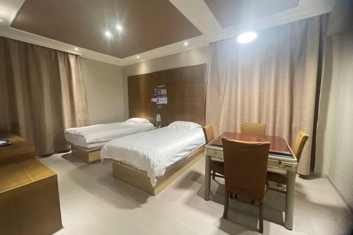 Ein Hotelzimmer mit zwei Betten, einem Schreibtisch und einem Stuhl.