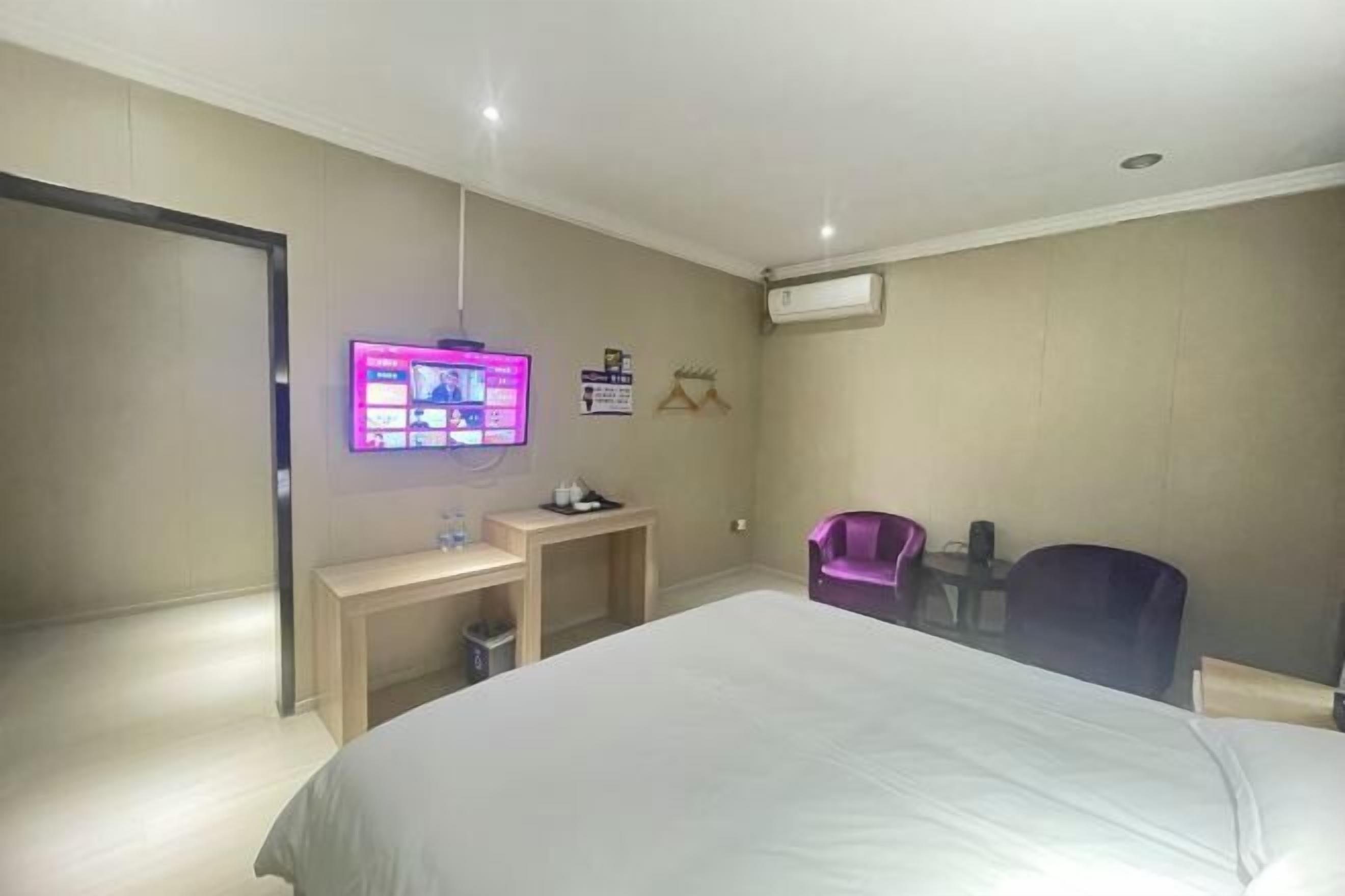 Habitación de hotel con cama, escritorio, silla, televisor y aire acondicionado instalado en la pared.