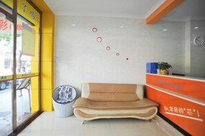 Un espace d’accueil comprenant un canapé, une poubelle et un mur décoré de motifs circulaires.