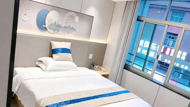 A hotel room with a bed, a nightstand, a phone, and a window with curtains. - the 80youth Chain Hotel from Dongguan (Dongguan)