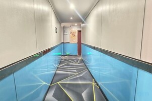 Un pasillo con piso de diseño azul y negro, que conduce a una puerta al final.