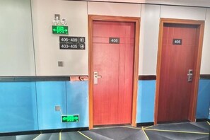 Un couloir d’hôtel avec deux portes, l’une portant le numéro 406 et l’autre le numéro 405, et un panneau vert indiquant la sortie de secours.