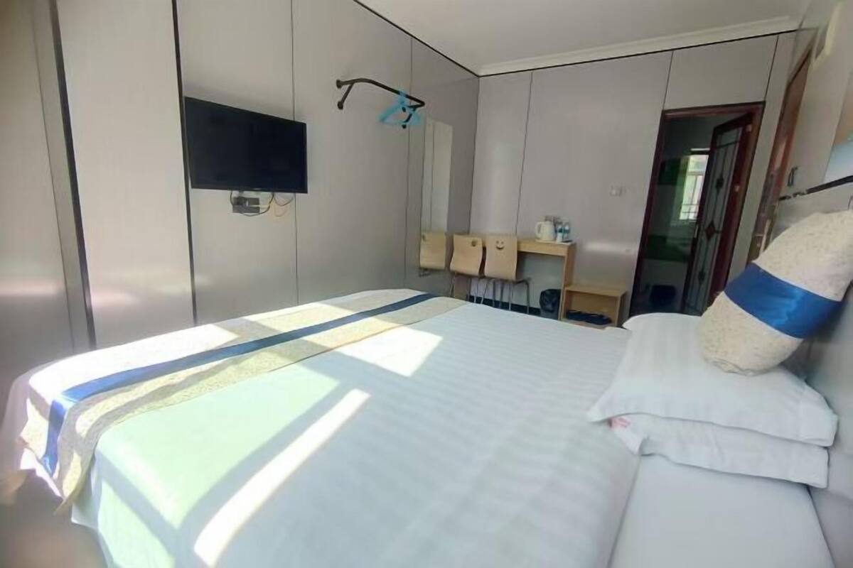 A hotel room with a bed, a TV mounted on the wall, and a towel rack.