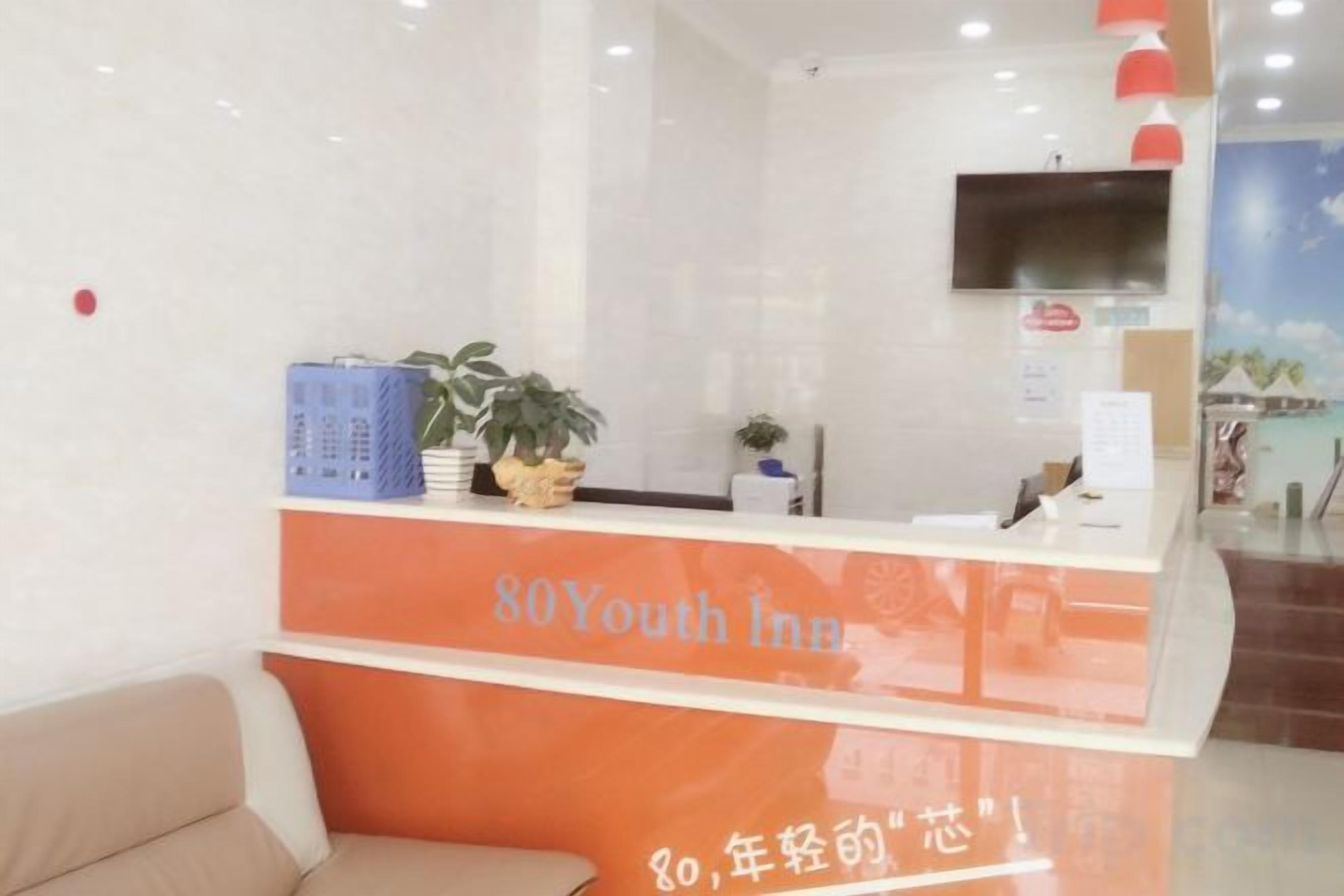 A reception desk with a sign reading '80Youth Inn' and a potted plant on it.