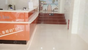 A hotel reception area with a reception desk, a staircase, and a tropical-themed wall mural. - the 80youth Chain Hotel from Dongguan (Dongguan)