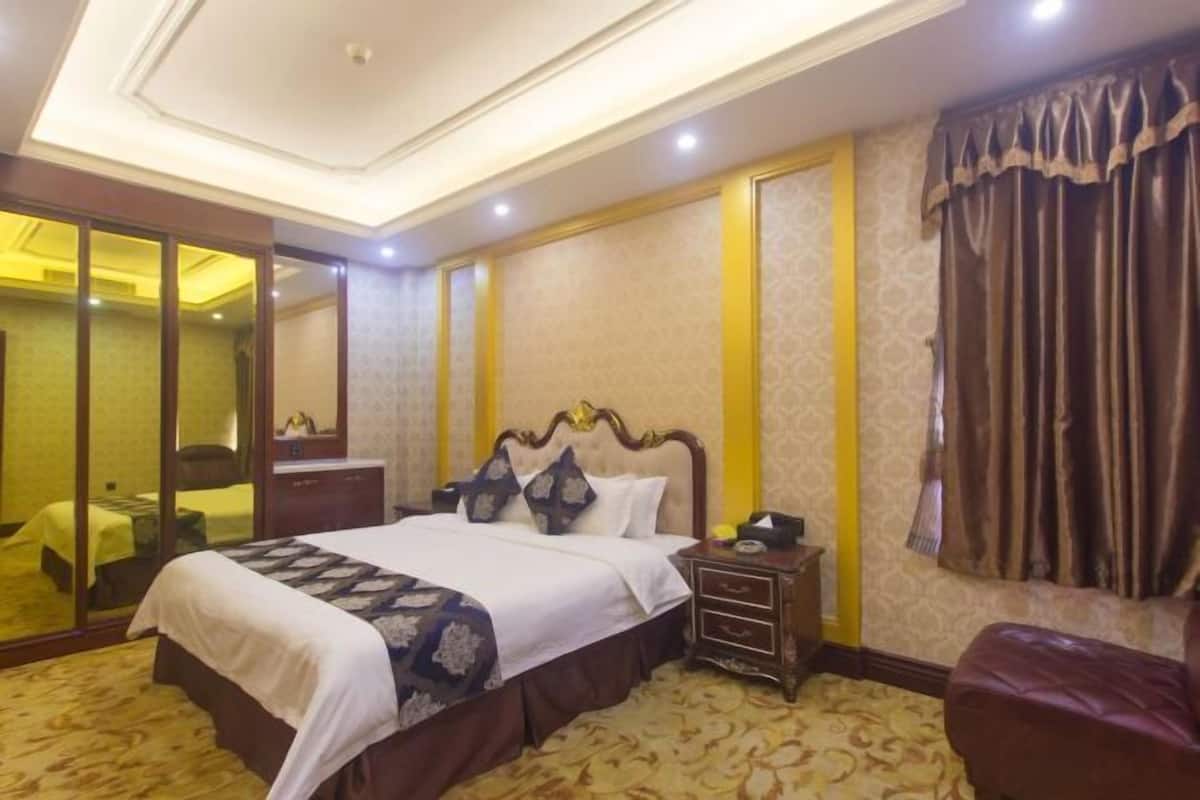 Ein Hotelzimmer mit einem großen Bett, einem Nachttisch, einem Spiegel und einem Fenster mit Vorhängen.