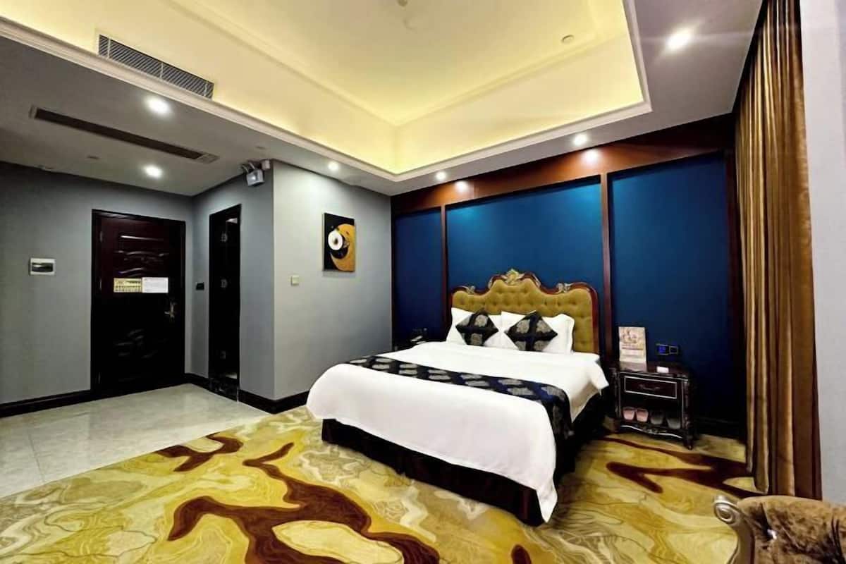 Ein Hotelzimmer mit einem großen Bett, einem Zierkopfende, einem Nachttisch mit Lampe und einem an der Wand befestigten Fernseher.