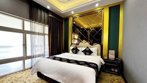 A hotel room with a large bed, a nightstand, a mirror, and a window with curtains. - Yijing Hotel (Zhongshan)