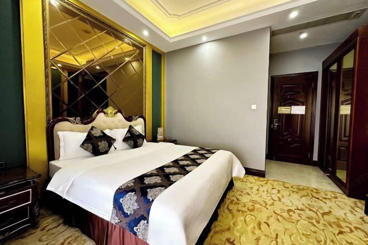 Ein Hotelzimmer mit einem großen Bett, einem Spiegel und einem Holzschrank.
