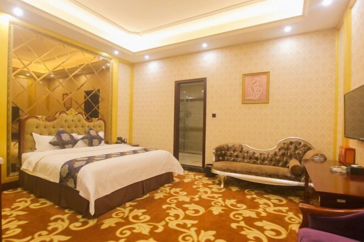 A hotel room with a large bed, a sofa, a small table, and a TV.