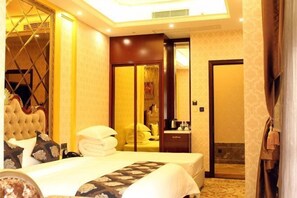 A hotel room with a large bed, a wardrobe, a bathroom, and a mirror. - Yijing Hotel (Zhongshan)