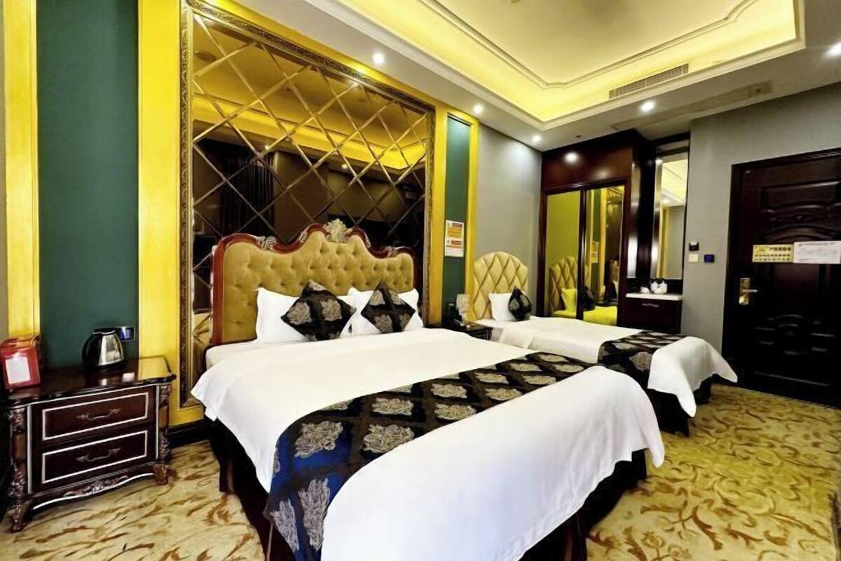 Ein Hotelzimmer mit zwei Betten, einem großen Spiegel, einem Kleiderschrank und einer dekorativen Wandverkleidung.