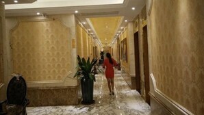 A marble-floored hallway with ornate wall designs and a chandelier. - Yijing Hotel (Zhongshan)