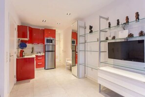 Kitchen features a microwave, refrigerator, and glass display shelf.