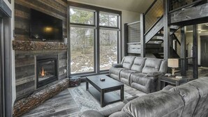 A modern living room with a fireplace, leather sofas, and a staircase. - Wernski Lodge – Stunning Views, Hot Tub & Spacious Retreat (Lead)