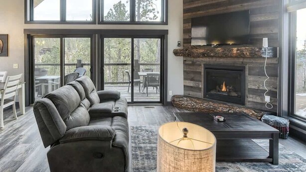 A modern living room with a leather sofa, a fireplace, and large windows. - Wernski Lodge – Stunning Views, Hot Tub & Spacious Retreat (Lead)