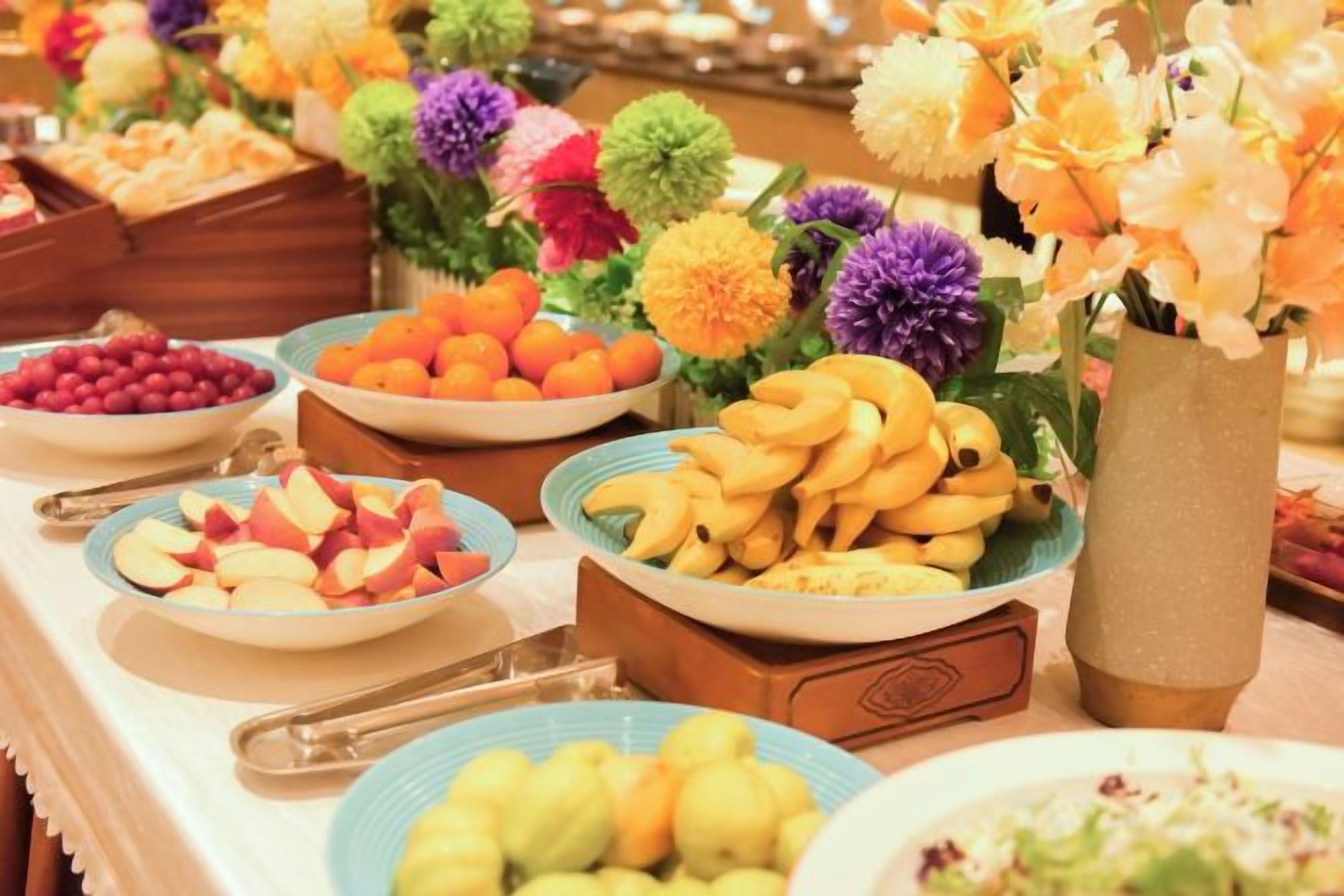 Una mesa de buffet con diversos alimentos y flores decorativas.