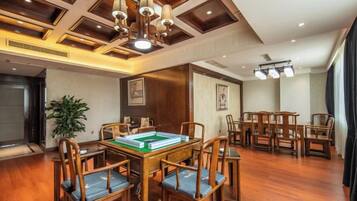 A spacious room with a pool table, wooden chairs, and a ceiling with recessed lighting.