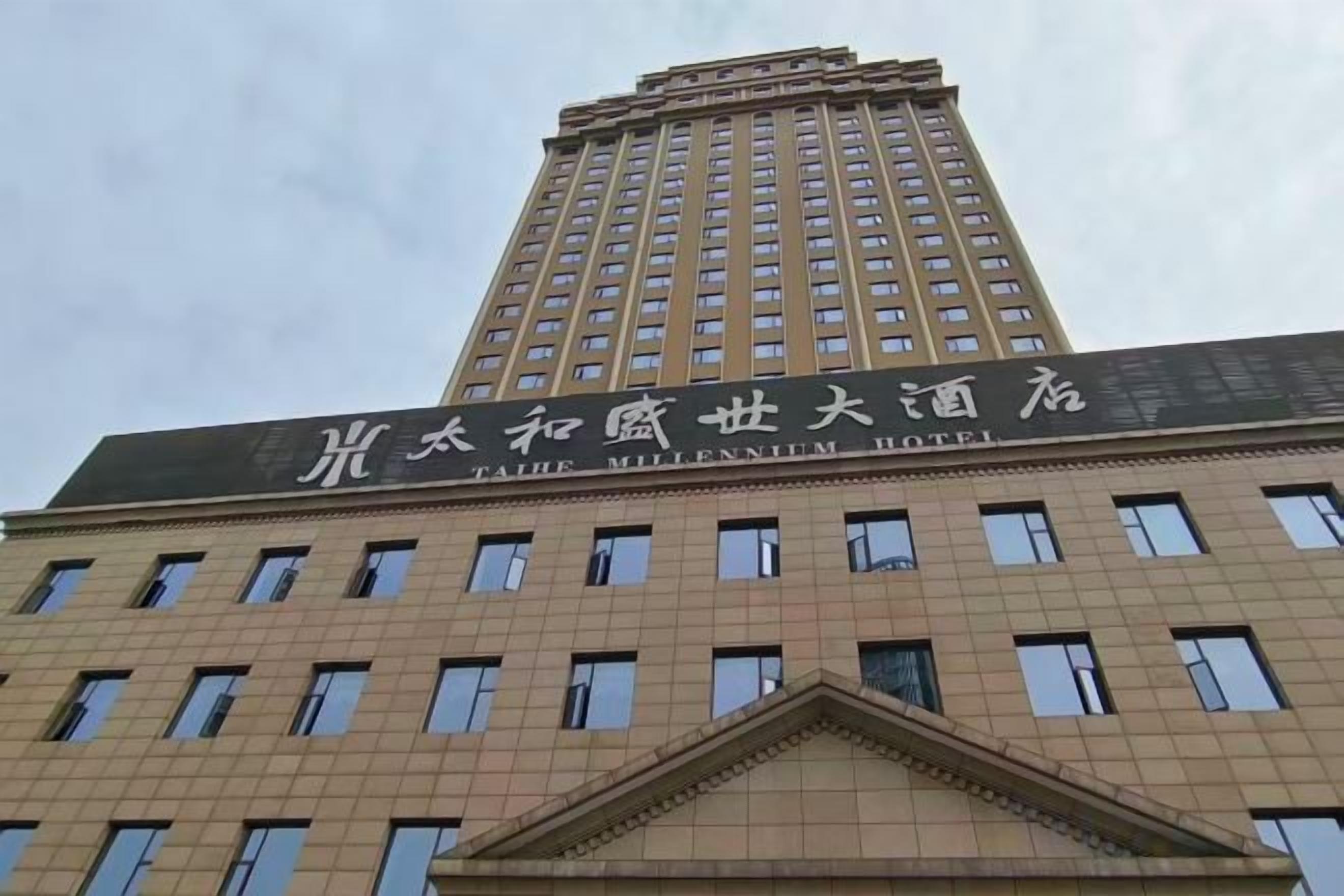 A tall building with a sign indicating it is the 'Taibei Millennium Hotel.'