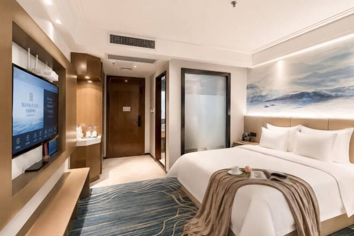 Une chambre d’hôtel avec un lit, une télévision, un bureau et une fenêtre donnant sur un paysage agréable.