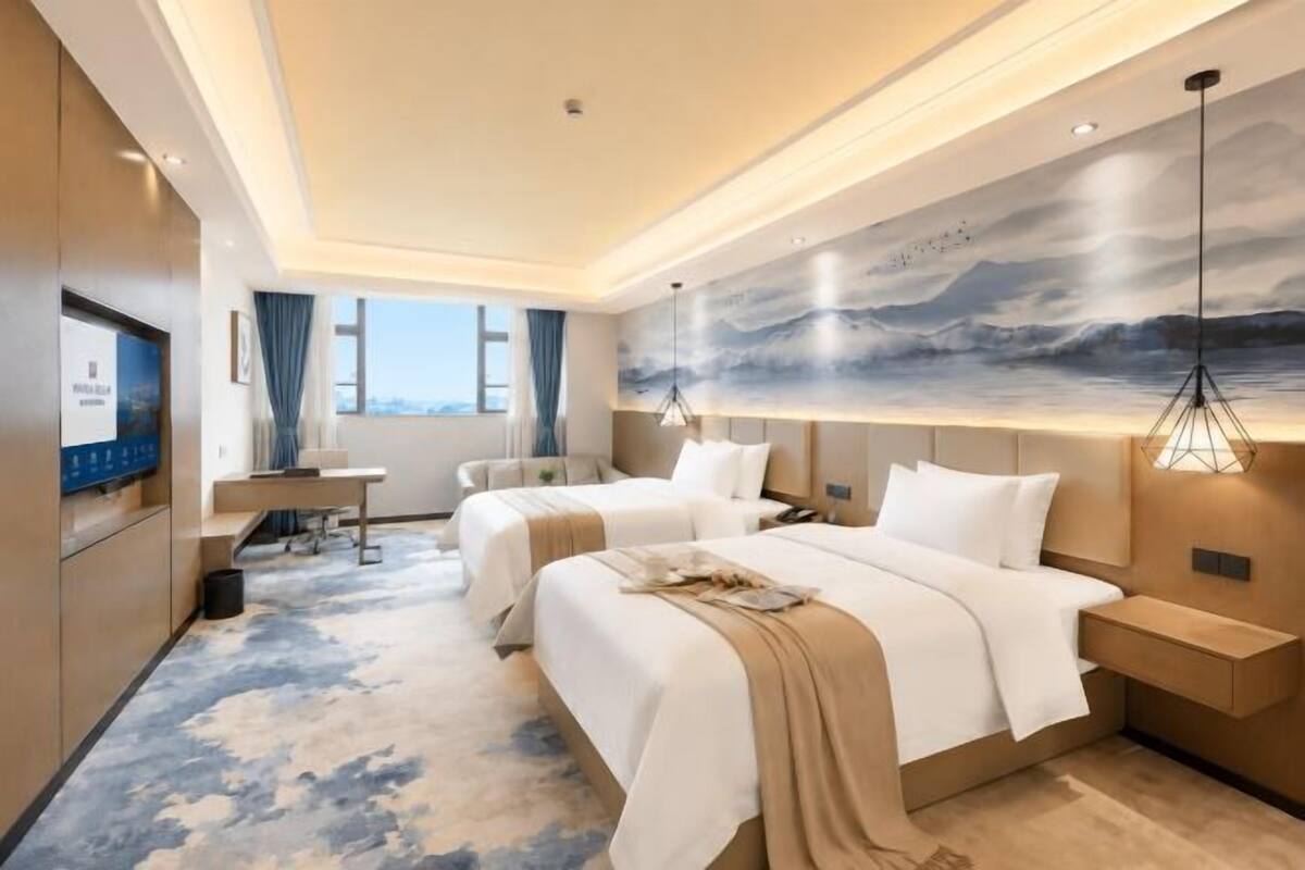 Une chambre d’hôtel avec deux lits, un bureau, une télévision et une grande fenêtre.