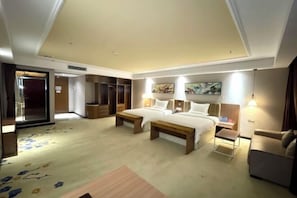 A hotel room with two beds, a sofa, a desk, and a wardrobe.