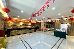 A hotel lobby with a reception desk, seating area, and a large wall mural. - Jinxiu Xiangjiang Hotel (Foshan Jinsha) (Foshan)