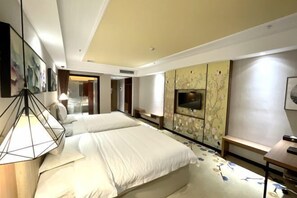 Quarto de hotel com duas camas, televisão, escrivaninha e uma janela grande.
