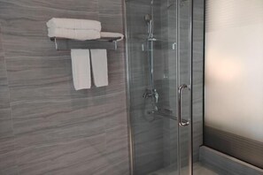 A modern bathroom with a glass shower enclosure, a towel rack with two towels, and a marble wall. - Jinxiu Xiangjiang Hotel (Foshan Jinsha) (Foshan)