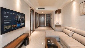 A modern living room with a flat-screen TV, a sofa, a coffee table, and a hallway leading to other rooms. - Jinxiu Xiangjiang Hotel (Foshan Jinsha) (Foshan)