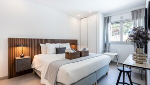 Ein modernes Hotelzimmer mit einem großen Bett, Nachttischen, einem Schreibtisch und einem Fenster mit Vorhängen.