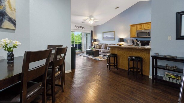 A modern kitchen with wooden cabinets, a microwave, and a dining area with a table and chairs. - Holiday Ridge Retreat 10 - Holiday Hills Branson - Golf Resort - Outdoor Pools (Branson)