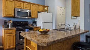 A kitchen with wooden cabinets, stainless steel appliances, granite countertops, and a fruit bowl. - Holiday Ridge Retreat 10 - Holiday Hills Branson - Golf Resort - Outdoor Pools (Branson)