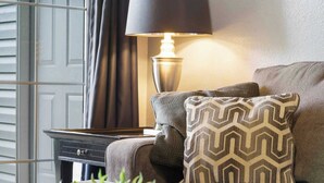 A cozy living room with a sofa, a patterned throw pillow, a lamp, and a plant. - Holiday Ridge Retreat Duo - Holiday Hills Branson - Golf Resort - Outdoor Pools (Branson)