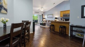 A modern kitchen with wooden cabinets, a microwave, and a dining area with a table and chairs. - Holiday Ridge Retreat Duo - Holiday Hills Branson - Golf Resort - Outdoor Pools (Branson)
