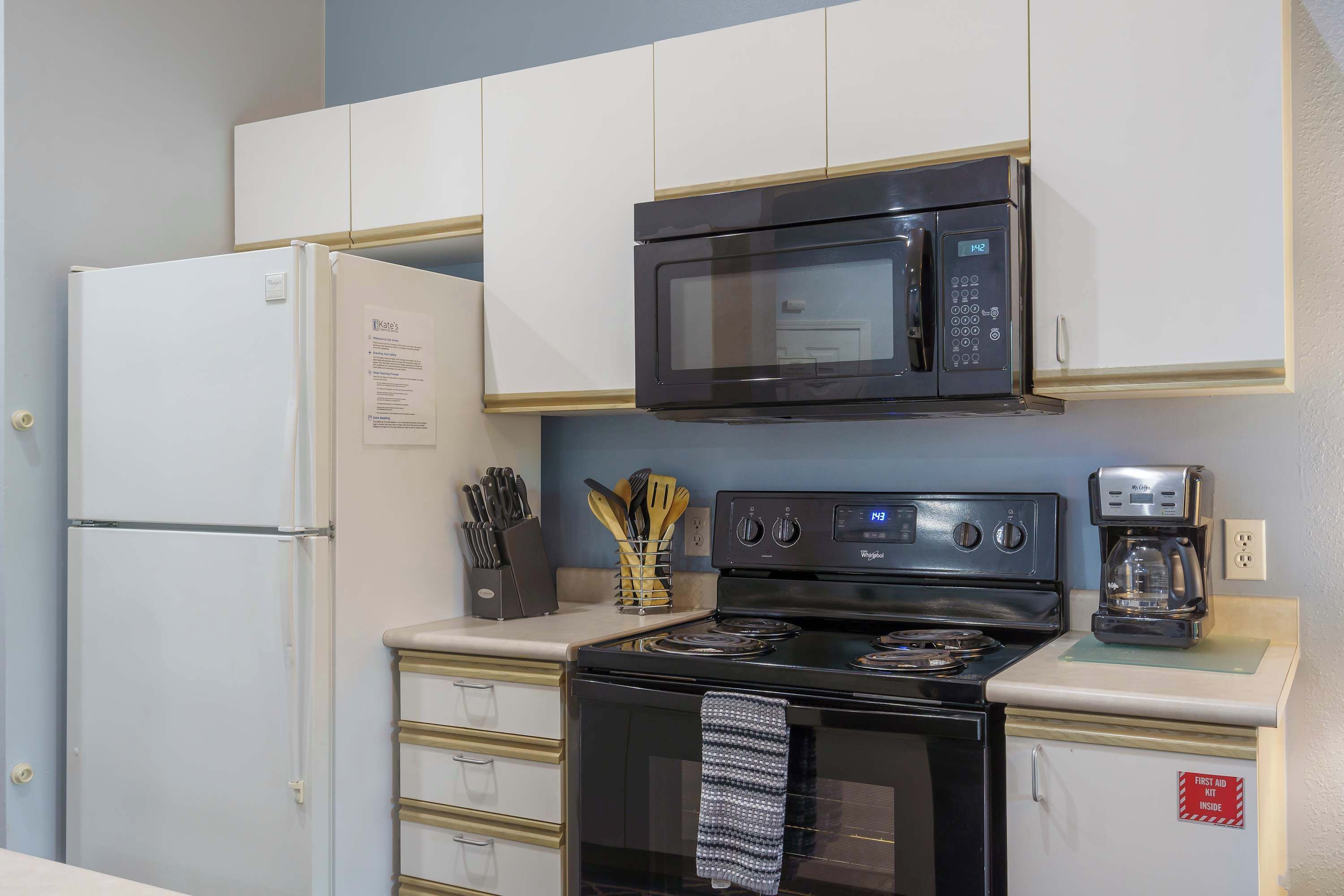 A compact kitchen with a refrigerator, microwave, stove, and a coffee maker.