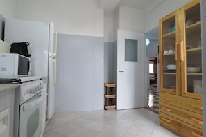A kitchen with a white refrigerator, microwave, and oven. There is a wooden cabinet with glass doors.