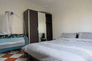 A bedroom with a bed, a wardrobe, and a nightstand.