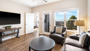 A modern living room with a flat-screen TV, a round coffee table, a leather sofa, and a ceiling fan. - Our Happy Place in the Heart of Branson (Branson)