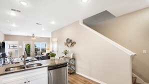 A modern kitchen with a dishwasher, a sink, and a dining area with chairs and a table. - Our Happy Place in the Heart of Branson (Branson)